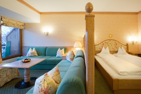 Wohn- und Schlafbereich des Komfort Doppelzimmer Lech am Arlberg Komfort Doppelzimmer in Lech am Arlberg im Landhaus Sonnenburg mit Doppelbett und Sitzmöbeln