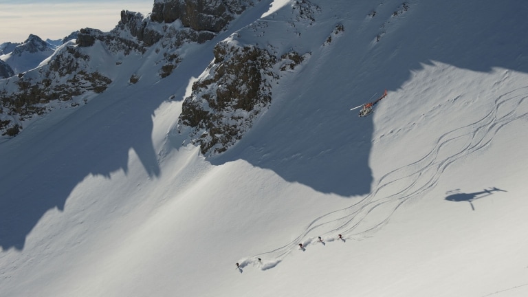 Symbolbild für Heliskiing Arlberg: Helikopter fliegt über Skifahrern in den Arlberger Alpen