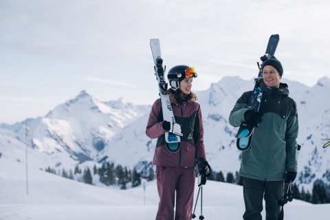 Symbolbild für Lech Hotels Ski in Ski out: Zwei Skifahrer tragen ihre Skiausrüstung