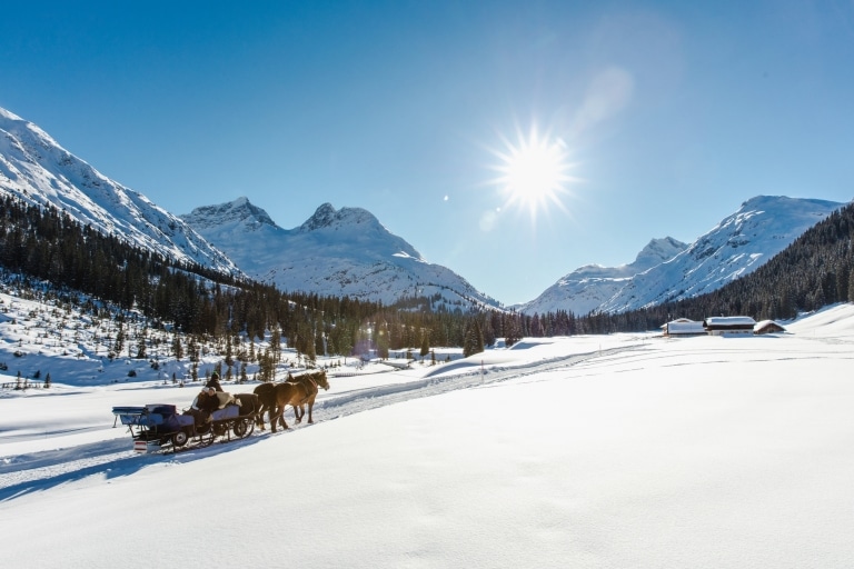 Pferdeschlittenfahrt am Arlberg vor verschneiter Berglandschaft