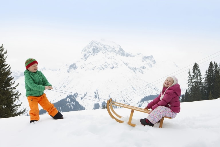 Kinder spielen im Familienurlaub vor dem Family Hotel Sonnenburg im Schnee