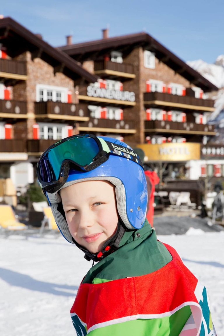 Bub mit Skihelm besucht die Skischule im Familien-Skiurlaub