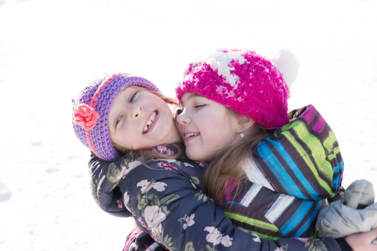 Zwei Mädchen umarmen sich im Schnee