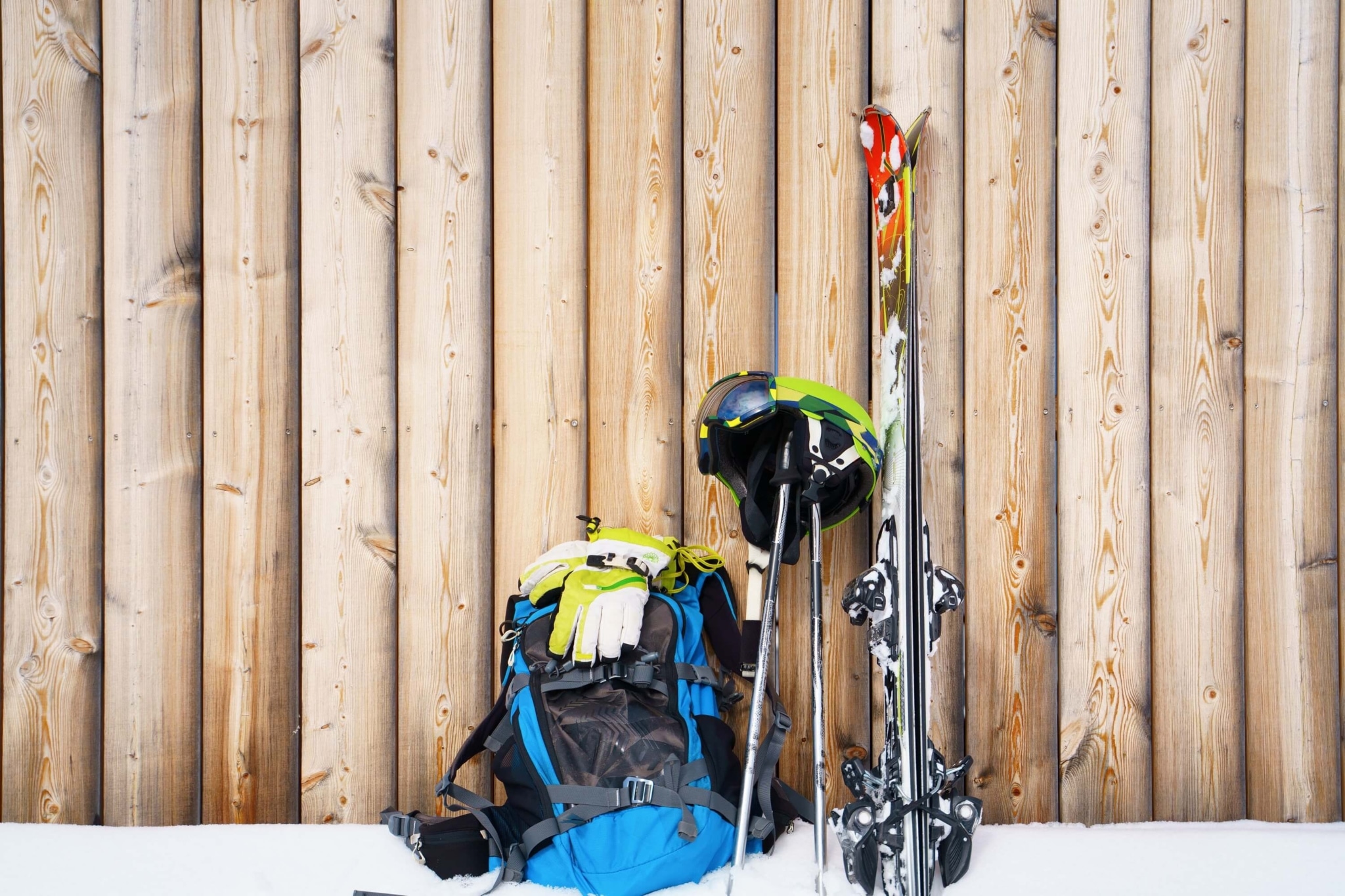 Skiausrüstung steht im Schnee vor einer Holzhütte