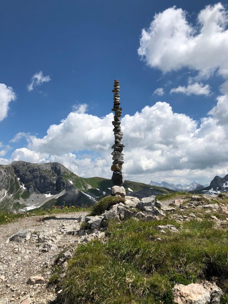 Turm aus Steinen neben dem Geoweg Rüfikopf, dahinter strahlend blauer Himmel