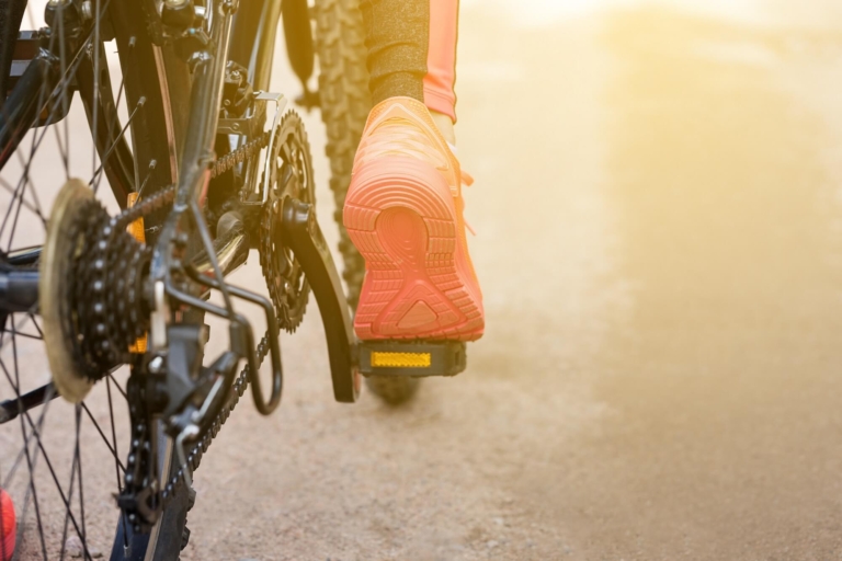 Frau mit roten Sportschuhen tritt in die Pedale ihres Fahrrades (Nahaufnahme)