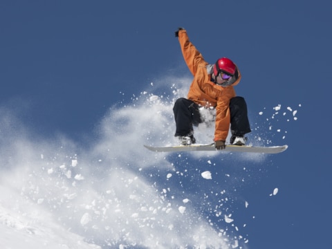 snowboard-sprung Snowboarder springt über einen Kicker in Lech