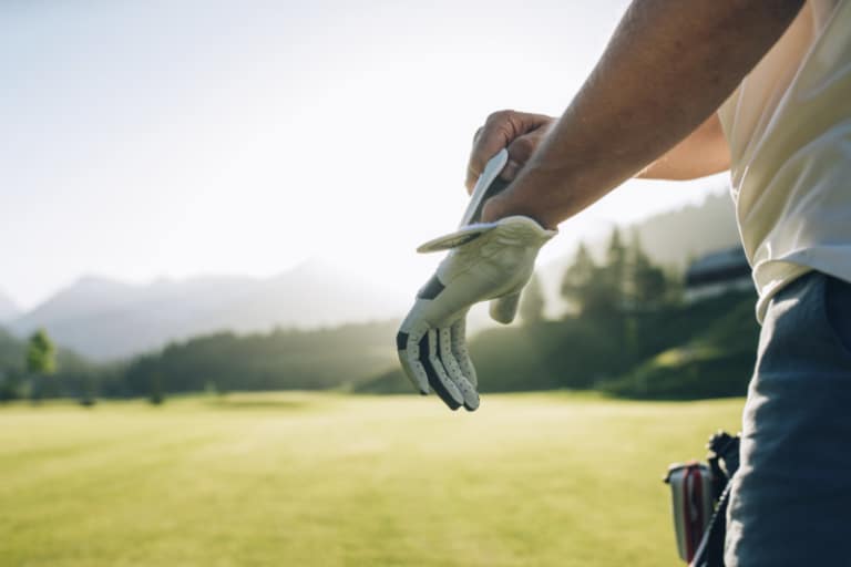 Mann zieht Golfhandschuh an