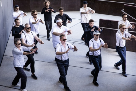 Tanzcafe Lech 2023 Eröffnungskonzert Sonnenburg Terrasse (1) Ein Ensemble von Tänzern in eleganter Kleidung präsentiert eine kreative Choreografie im Freien.