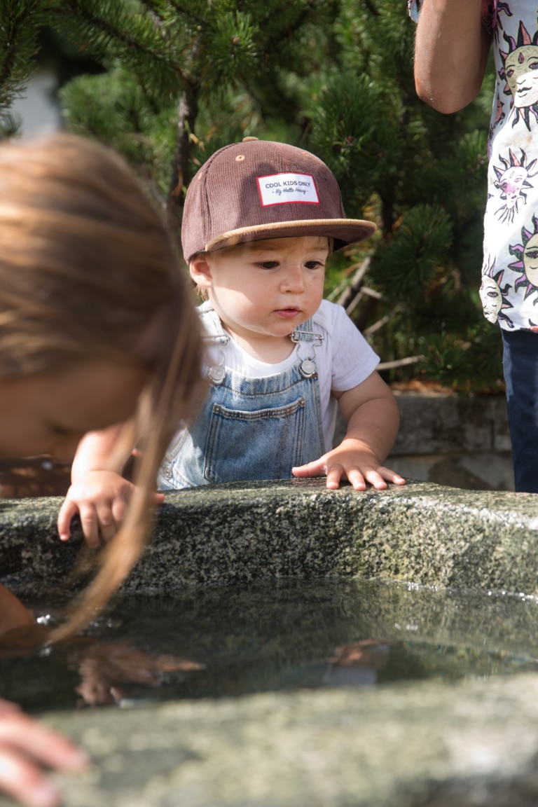 Symbolbild für Sommerurlaub in den Bergen mit Kindern: Kleinkind spielt am Wasser