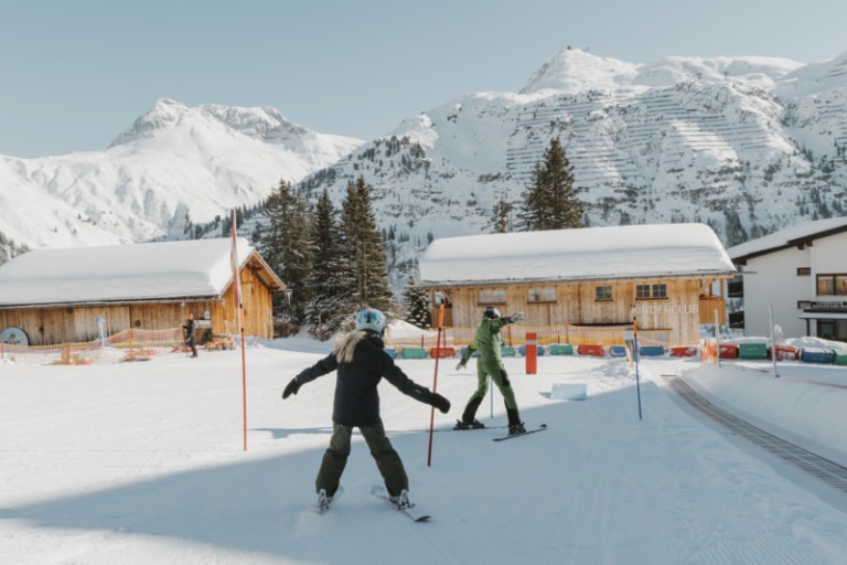 Zwei Kinder fahren mit den Ski ein Slalom in Oberlech