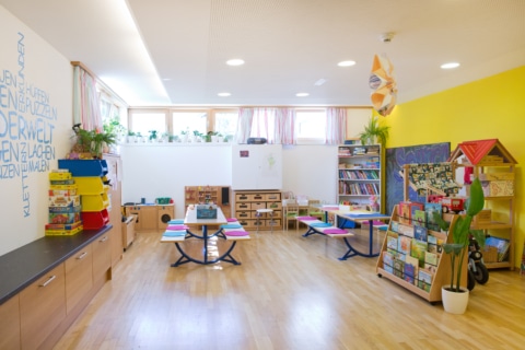 Sonnenburg_Gebaeude_Raeumlichkeiten_Stammhaus_Kinderwelt_Sommer_2024 Heller, einladender Raum für Kinder mit Spielmöglichkeiten und Regalen voller Bücher und Spiele.