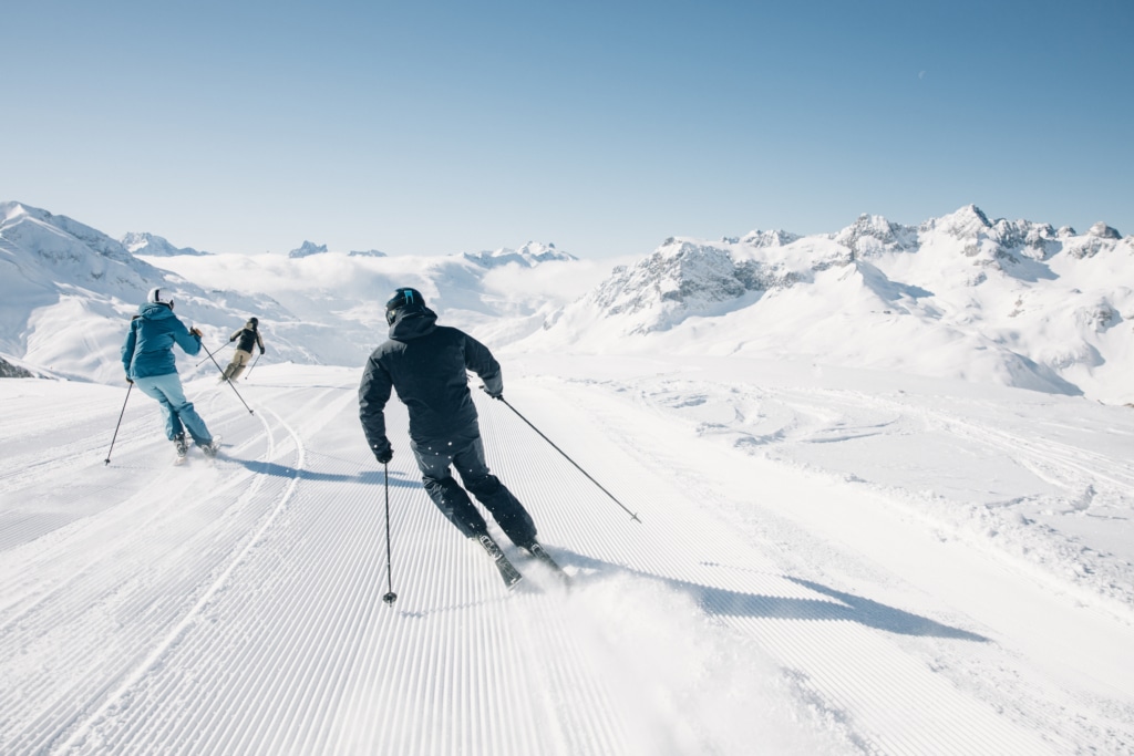 Skifahren in Lech Zürs (c) Daniel Zangerl Skifahrer auf der Piste mit Bergen im Hintergrund