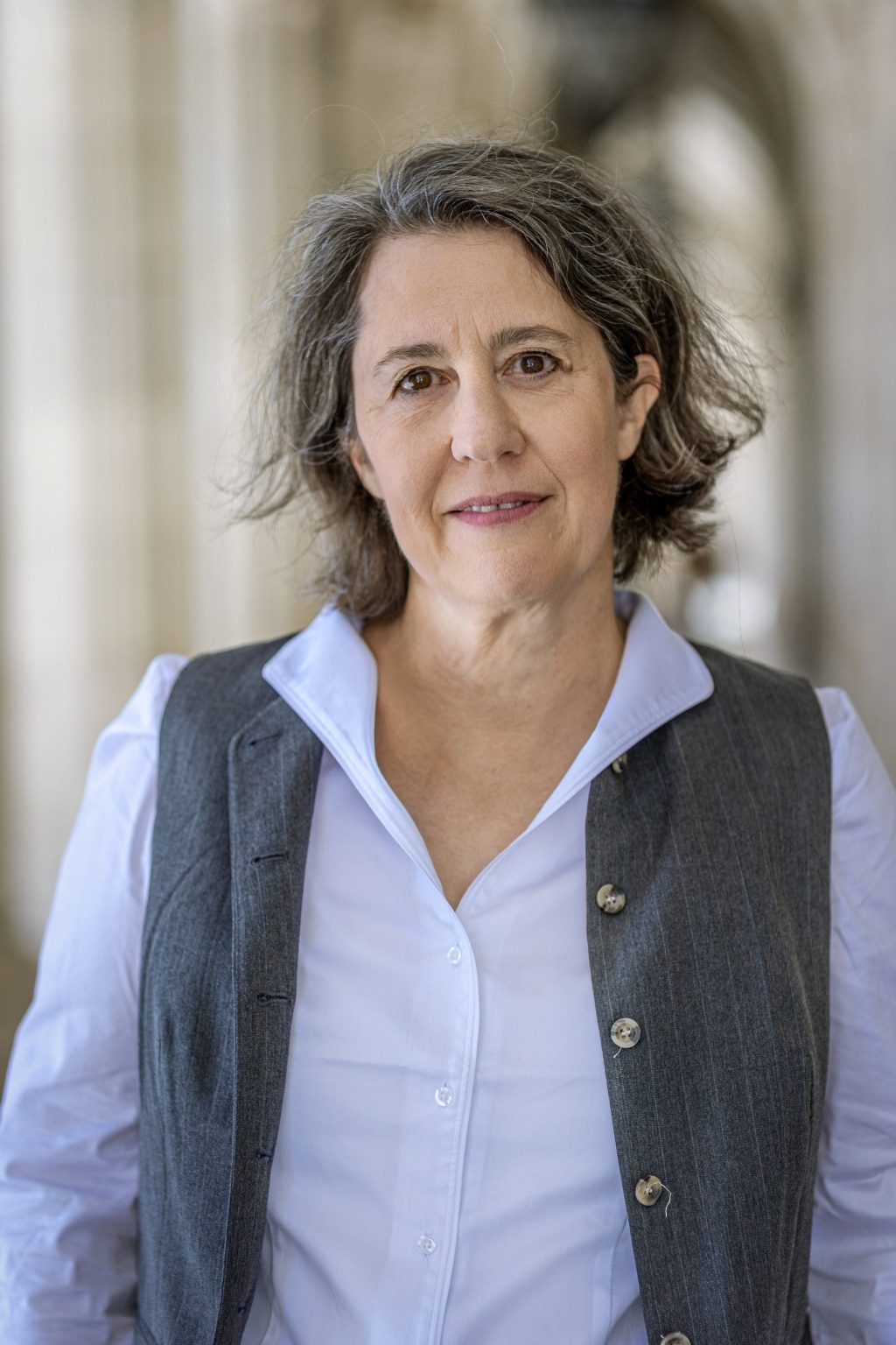 ©Ulrik Hölzel_klassisch Portrait der Autorin Petra Hartlieb mit Blauser Hemdluse bei Tageslicht vor einem Gebäude